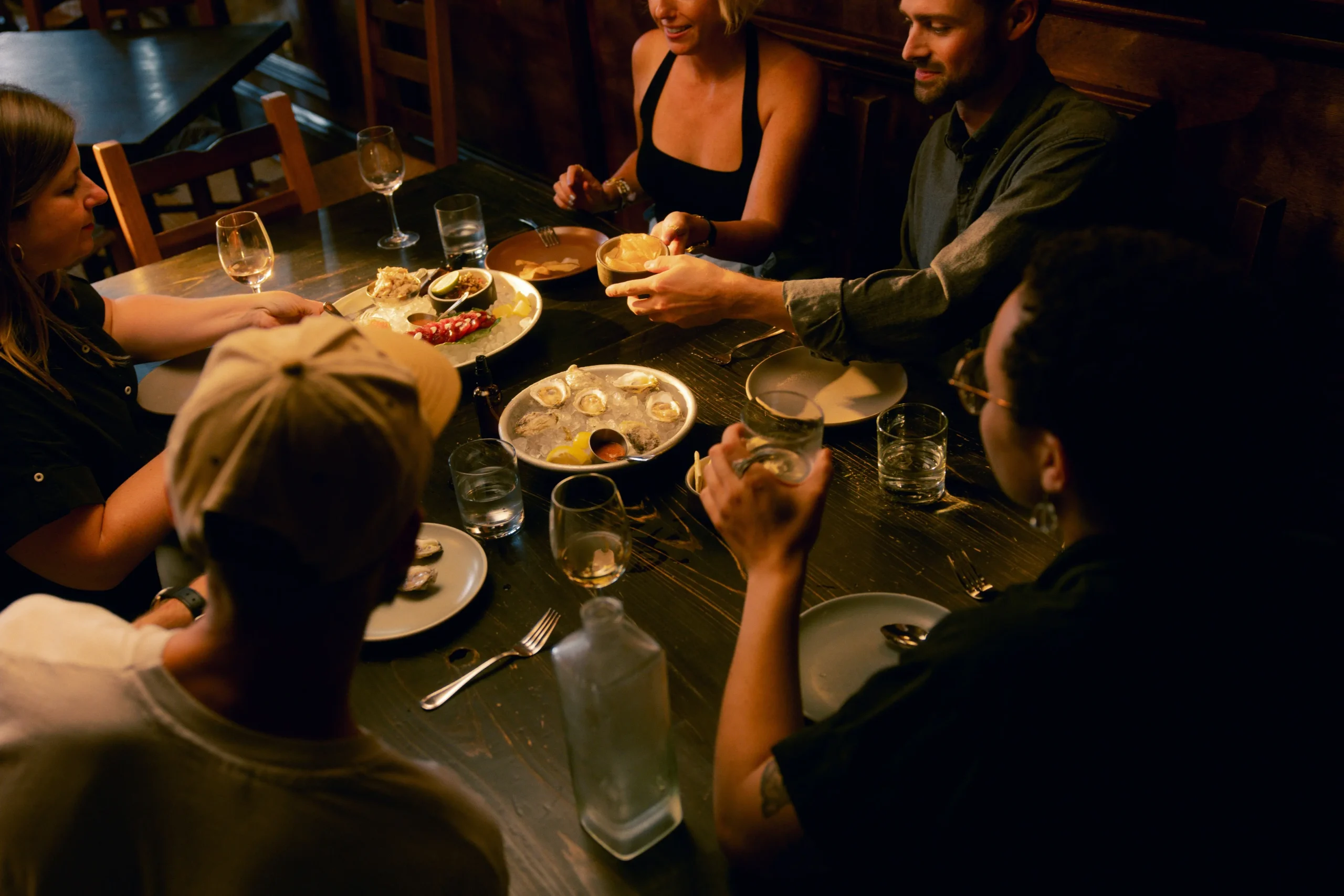 Group of people sharing a meal in a warm, intimate setting, fostering connection and mindful conversations, reflecting a travel mindset community