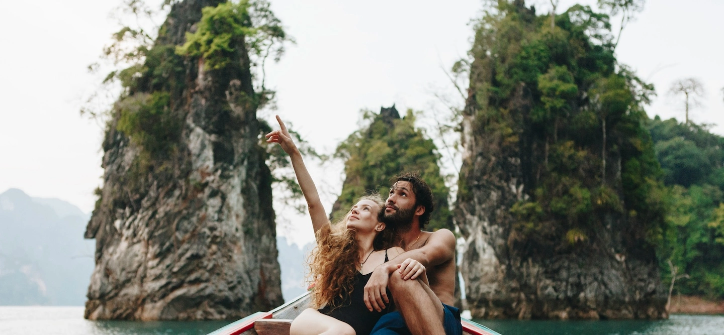 Travelers embracing the moment together on a boat, exploring breathtaking natural scenery, representing mindfulness, adaptability, and authentic connection during their journey.